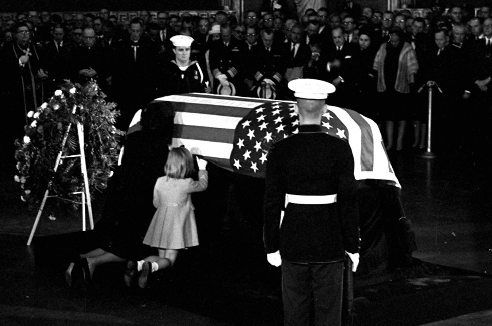 16.1963年11月24日，美国国会大厦圆形大厅内，杰奎琳-肯尼迪亲吻着丈夫的灵柩。边上陪同她的是他们的大女儿卡罗琳。