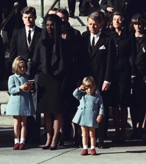 21.1963年11月25日，年仅3岁的小约翰-F-肯尼迪向父亲的灵柩致敬。杰奎琳与卡罗琳也在边上陪同。