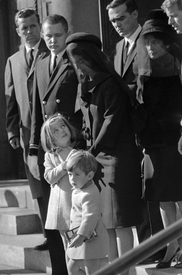 24.1963年11月25日，在离开圣马修大教堂时，5岁的卡罗琳-肯尼迪看着自己的母亲杰奎琳-肯尼迪。葬礼当天同时还是小约翰-肯尼迪的3岁生日，卡罗琳再过2天也6岁了。