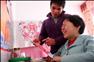12月11日，罗忠木（左）拿着妻子吕元芳制作的剪纸工艺品，逗妻子开心。新华社记者 张锰 摄