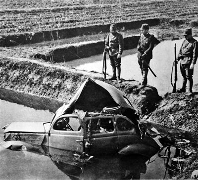 图为日军随军记者拍摄，日军正在观测被我军地雷炸毁掀翻的汽车。