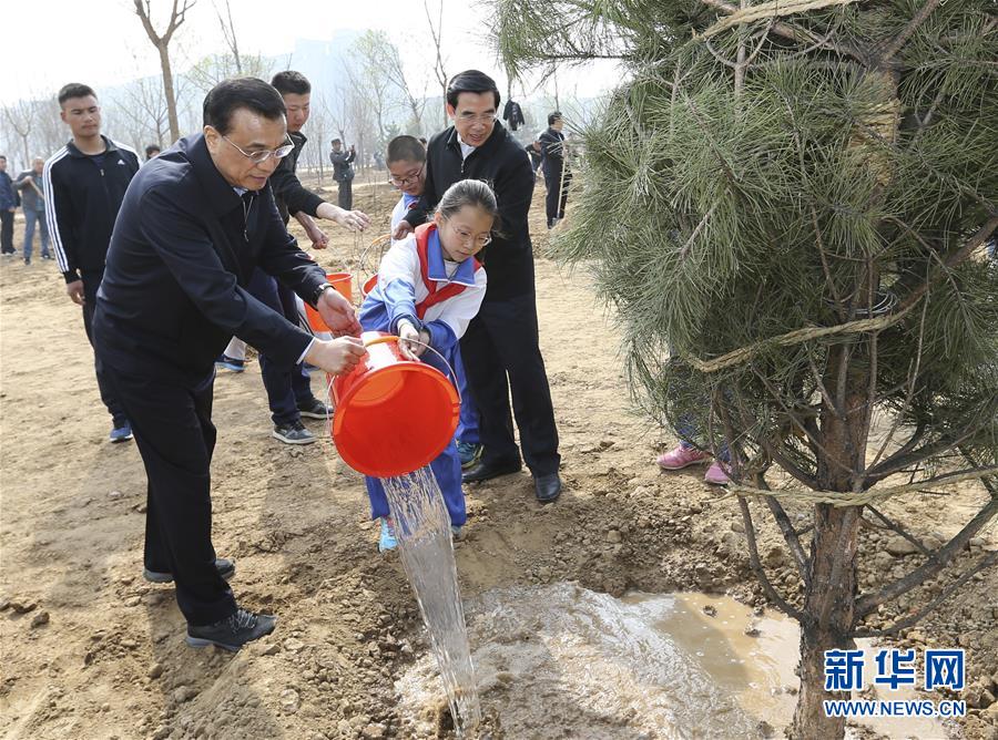这是李克强同少先队员一起给刚栽下的树苗浇水。 新华社记者 马占成 摄
