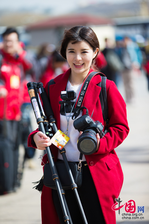 2016年两会，人民大会大堂前，一位笑容灿烂的红衣女记者正步入大会堂。中国网 郑亮 摄