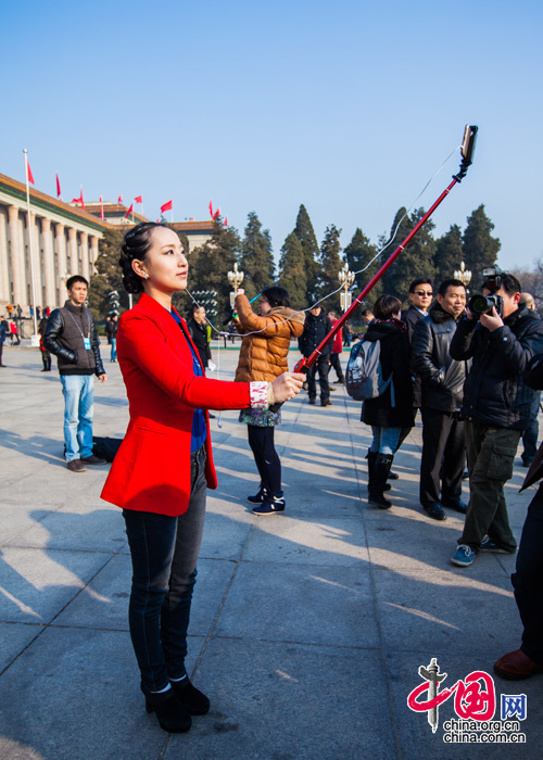 2016年3月5日，身穿红色大衣的中国网女记者佟静在人民大会堂前留影。中国网 郑亮 摄