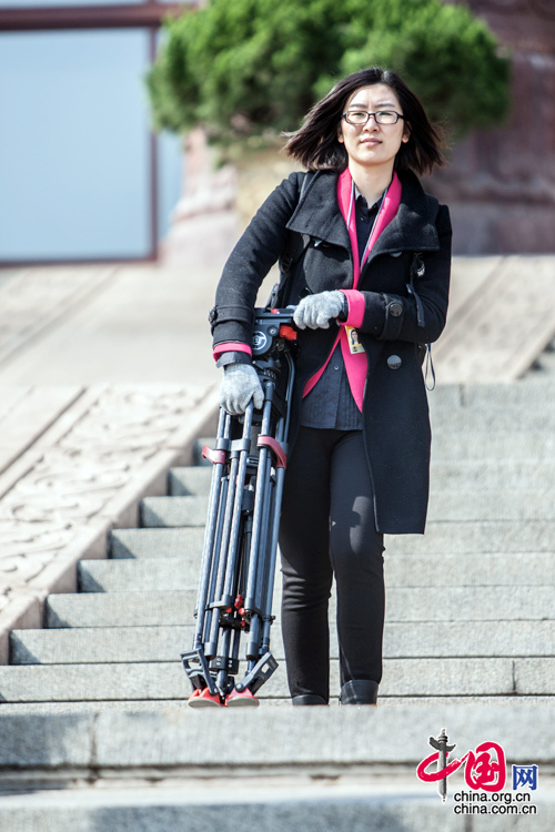  2015年3月5日，第十二届全国人大第三次会议开幕，一名女记者正准备入场，玫红外套上面的黑色大衣也遮盖不了这一抹亮色。中国网 郑亮 摄