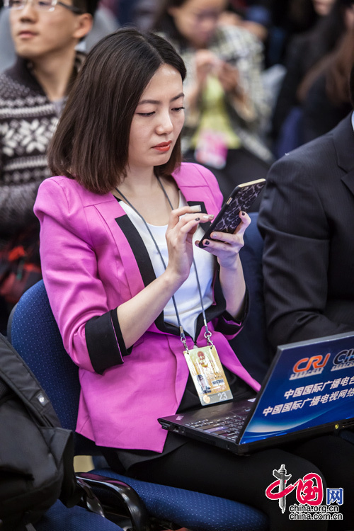 2015年3月8日，外长记者见面会，一位身穿玫红小西装的女记者在大会前做准备。中国网 郑亮 摄
