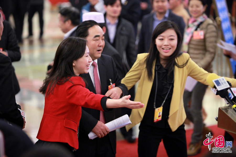 2013两会，一位着红色小西装的女记者为“请”部长也是“蛮拼的”。中国网 杨佳 摄