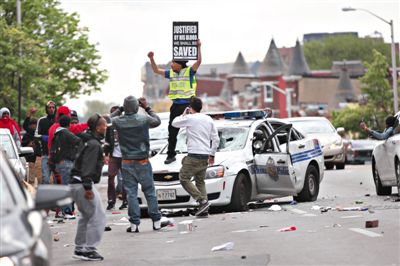 27日，美国巴尔的摩，抗议者摧毁一辆警车。当日，巴尔的摩示威抗议演变为大规模骚乱，当局被迫宣布进入紧急状态。