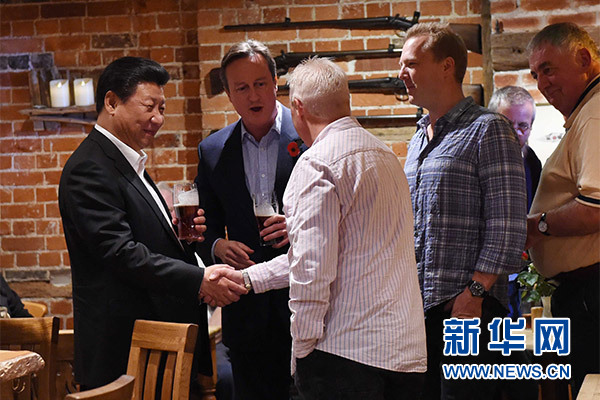 这是习近平与卡梅伦饮啤酒，并同当地民众交谈。新华社记者 饶爱民 摄