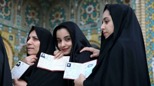 伊朗民众在投票前展示身份证件。（美联社）