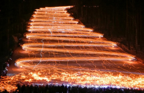 数百滑雪者手持火把滑雪 白色雪道变身“火天梯”