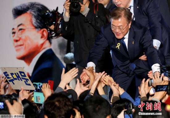 文在寅当选新一任韩国总统时，与民众握手。