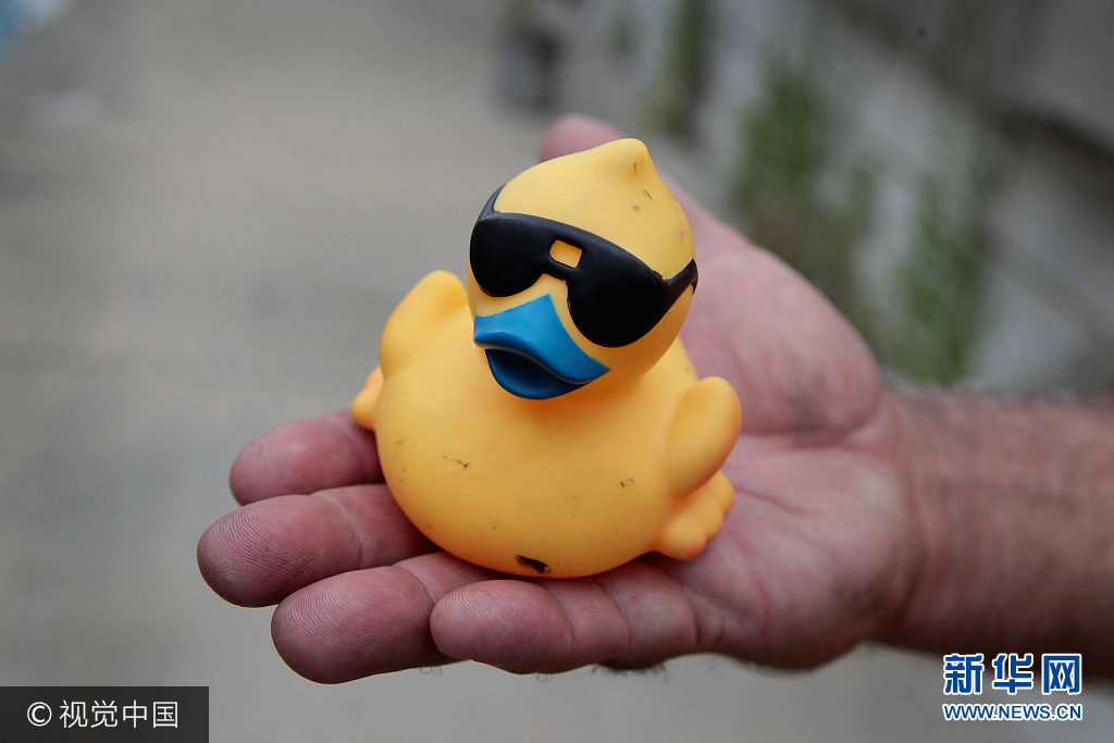 当地时间2017年8月3日，美国芝加哥，芝加哥举办一年一度的慈善筹款橡胶鸭比赛，约6万只“小黄鸭”从桥上倾泻至芝加哥河中，第一只漂过终点的小黄鸭的赞助者将获得一辆SUV汽车。***_***CHICAGO, IL - AUGUST 03: A volunteer holds a rubber duck recovered from the Chicago River following the Windy City Rubber Ducky Derby on August 3, 2017 in Chicago, Illinois. Derby organizers drop 60,000 rubber ducks from a bridge above the river to start a race which helps to raise about $350,000 for Special Olympics Illinois. The sponsor of the first duck to float across the finish line is awarded a new SUV.    (Photo by Scott Olson/Getty Images)