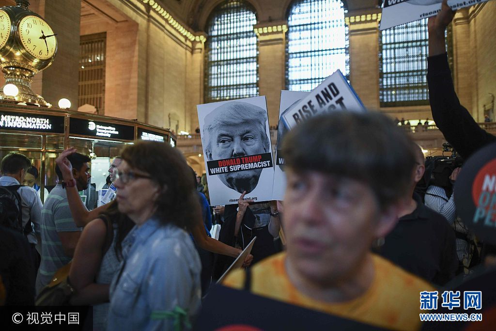 当地时间2017年9月18日，美国纽约，当地民众在纽约中央火车站集会，举行“反白人种族主义”集会，抗议总统特朗普。特朗普将在9月19日联合国大会首日发表演讲。***_***Protesters hold placards with slogans against US President Donald Trump during Rise and Resist Against White Supremacy demonstration inside the Grand Central Station in New York on September 18, 2017. US President Donald Trump will deliver his maiden address on Day One of the 72nd session of United Nations General Assembly on September 19, 2017. Jewel SAMAD