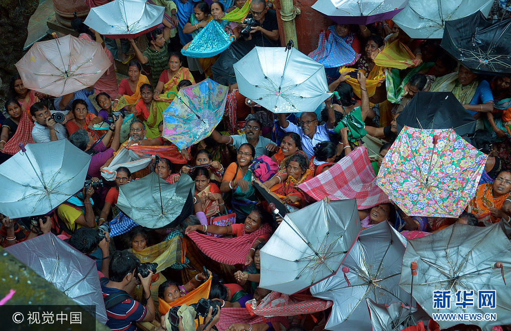印度信徒抢接“好运之米” 雨伞花布齐上阵